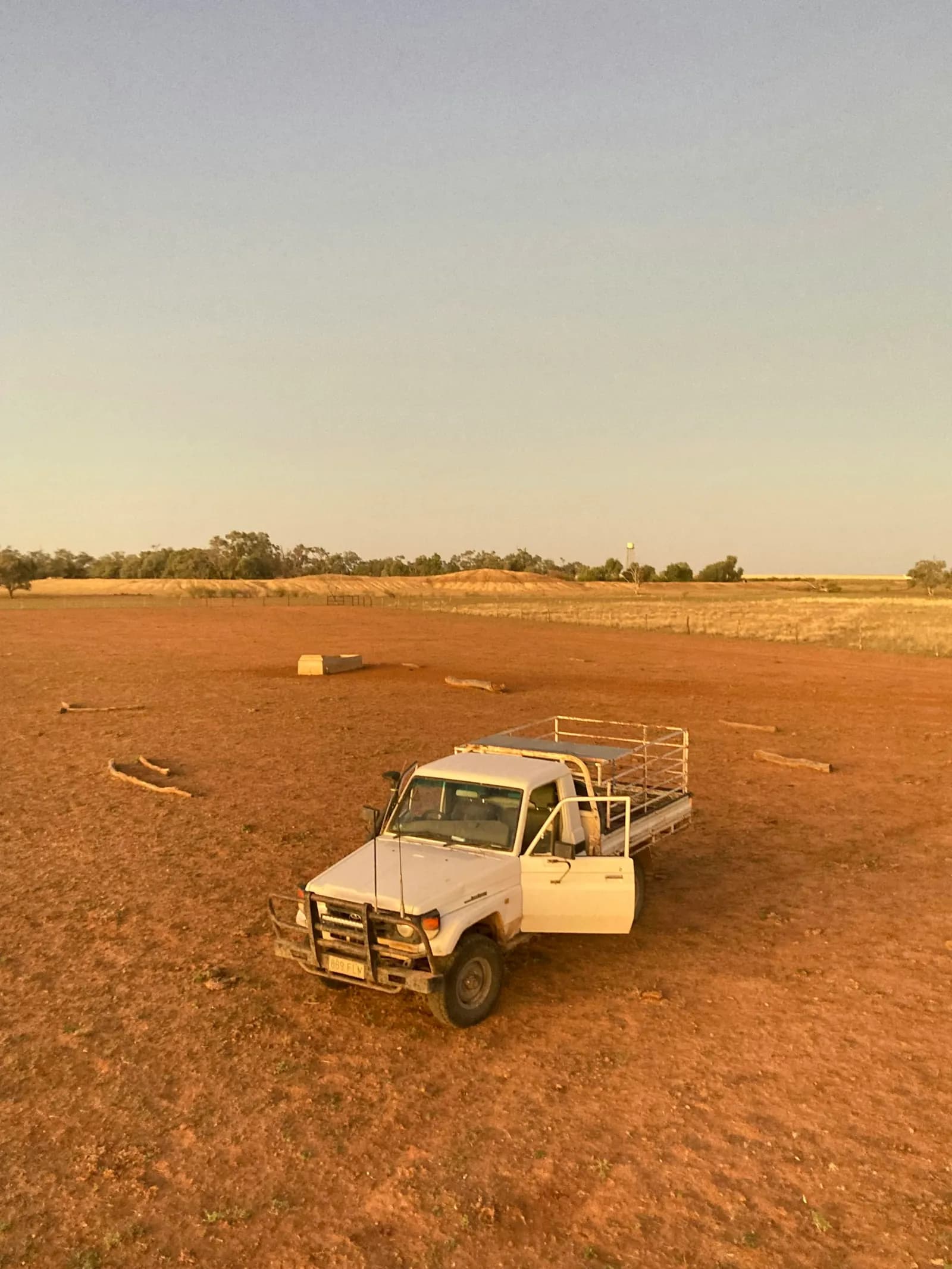 Tray-back ute parked in a dry paddock under an open sky